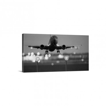 An Airplane Landing With Blurred Lights Of The Airport In The Background Wall Art - Canvas - Gallery Wrap